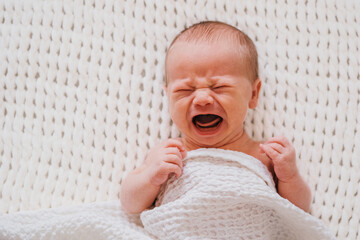 Closeup portrait of crying newborn baby boy. Soft focus.
