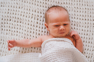 Closeup portrait of angry newborn baby boy. Soft focus.