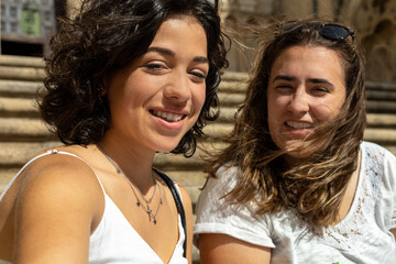 detail of a selfie photograph taken by two young Caucasian women smiling at the camera while sitting on the stairs