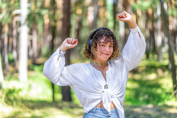 Pretty young woman listening to music in an oak forest.