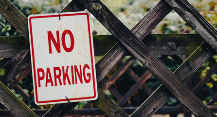 A no parking sign against a wooden fence