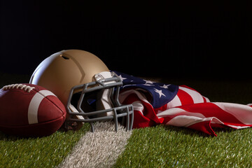 Low angle view of a football and helmet with American flag on a grass field with stripe