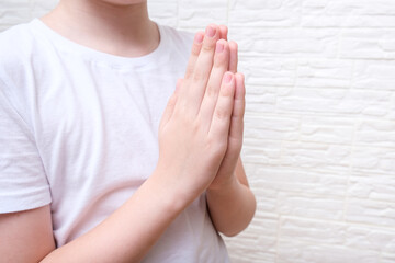 A boy showing gratitude gesture on white background, he is hopeful while praying
