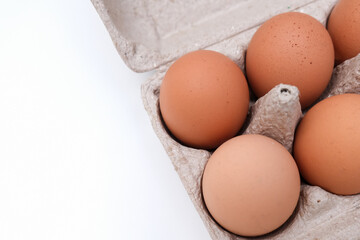 Brown chicken eggs in a carton box, container on white background with copy space close up