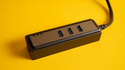 Close up black USB hub isolated on yellow. Three ports USB charger