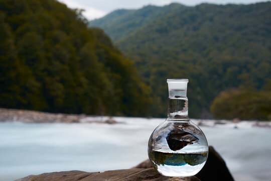Bottle of drinking water on the shore of a mountain river.