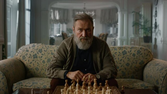 Thoughtful senior man thinking chess game home. Senior player playing chess