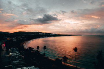 Beautiful seascape with coastline buildings and trees under a cloudy sky at sunset