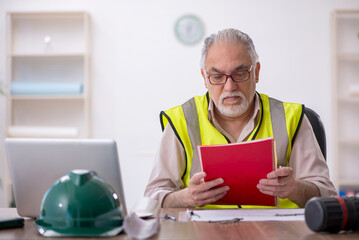 Old male architect working in the office