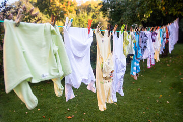 Baby cute clothes hanging on the clothesline outdoor. Child laundry hanging on line in garden.