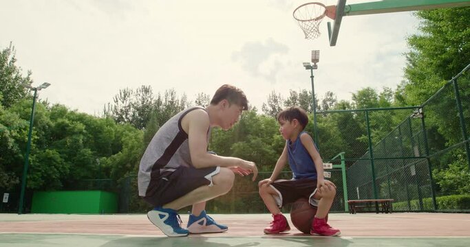 Father and son playing basketball in park,4K