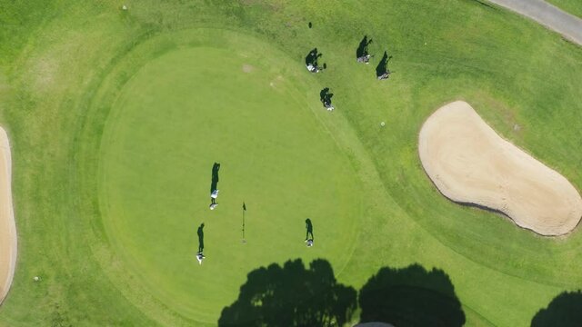 Top view of men playing golf game on field, Vale de Lobo, Algarve, Portugal, Europe. Aerial shot of male players practicing golf in meadow. Golf course with green grass. Sport concept, 4k footage