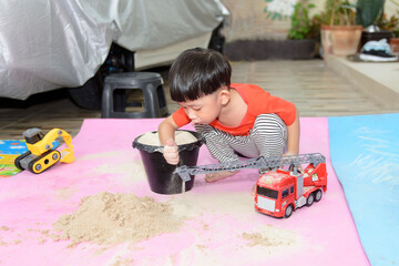 Little Asian boy playing with  sand alone at home, Child playing with toy construction machinery.Creative play for kids concept