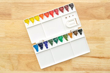 Watercolor paints set. Color in watercolor palette with wooden background.