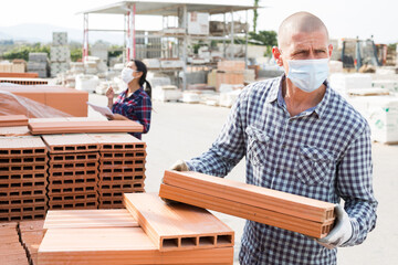 Builder in protecrive mask is choosing bricks in the building store