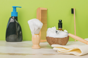 Items for shaving, washing and combing on a wooden table on a green background.