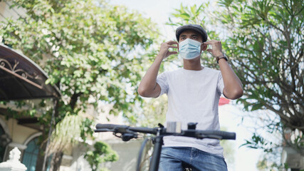 asian handsome man wear a mask while riding his bicycle