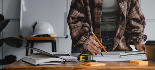 Cropped woman architect design working drawing sketch plans blueprints and making architectural construction model in architect studio.