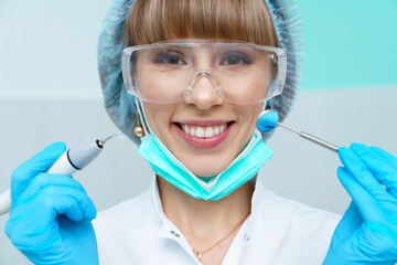 Young female dentist treating patient's teeth by filling cavity. Dentist works with professional...