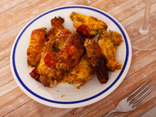 Appetizing baked chicken wings in a plate closeup