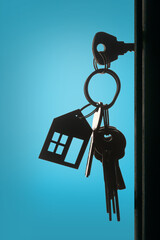 Silhouette of the keys with keyring in the door keyhole with blue background