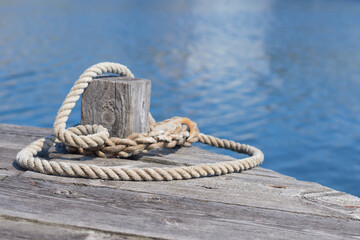 A mooring line around a bollard on a wooden pier