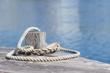 A mooring line around a bollard on a wooden pier