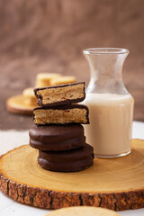 Stack of delicious chocolate chip cookies on white plate with milk bottles
