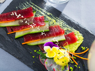 Delicious fresh tuna carpaccio dressed with cucumbers, carrot slices and edible flowers