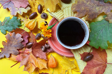 black coffee and autumn leaves on yellow background