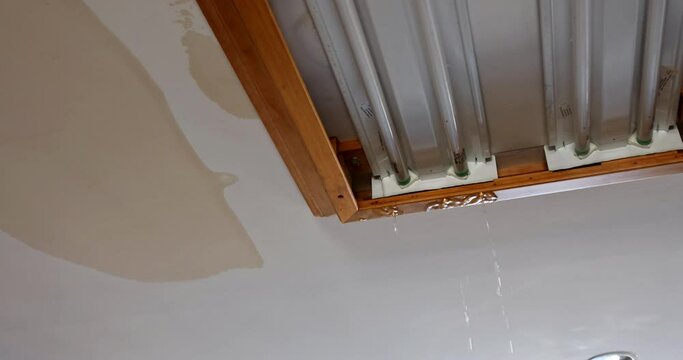 Leaking water running from ceiling light fixture due to burst water pipe
