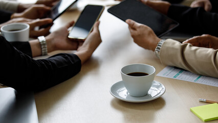 Unidentified unrecognizable businesspeople holding showing black blank digital touchscreen tablet and smartphone gadgets with copy space text together around work table in meeting room company office