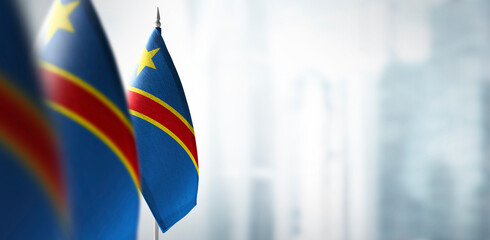 Small flags of Democratic Republic of the Congo on a blurry background of the city