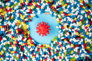 Studies to introduce anti-covid pills to fight the virus. Model of virus surrounded by various...