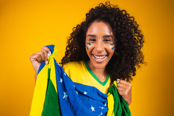 Afro girl cheering for favorite brazilian team, holding national flag in yellow background. .