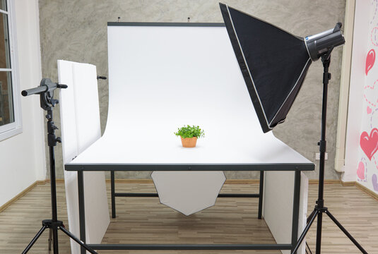 Indoor with air conditioner studio white photoshoot scene table and partition with professional photographer equipment softbox strobe flash reflector light on tripod stand ready for shoot products