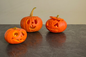 Halloween carved bright orange pumpkin jack lantern with different expressions of immotions on dark textured background
