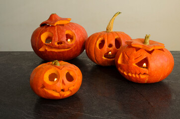 Halloween carved bright orange pumpkin jack lantern with different expressions of immotions on dark textured background