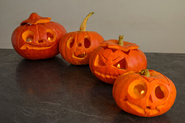 Halloween carved bright orange pumpkin jack lantern with different expressions of immotions on dark textured background