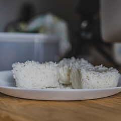 Boiled rice in a ceramic plate on wood table for cooking.