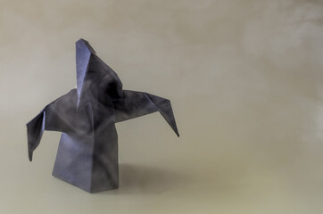 A dark paper ghost in clouds of fog on a dark background is a place for text.	