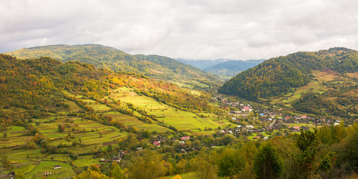 rural landscape in mountains. cloudy autumn weather. village in the distant valley