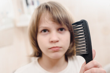 Portrait of young boy in bathroom combing hair in the morning, focus on comb foreground