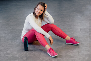 Plakat Middle age tired and relaxed woman in sportswear posing in modern gym