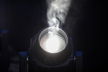 Shallow depth of field (selective focus) image with smoke and dust in the light of a stage reflector.