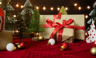 Gift box, christmas ball and christmas tree on red yarn wool with bokeh light background.