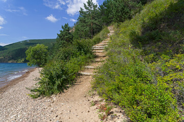 Fototapeta na wymiar Great Baikal Trail - a staircase on a rise on a high slope.