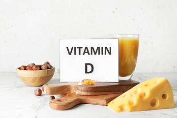 Text VITAMIN D and different healthy products on light background