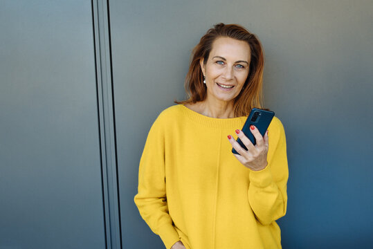 Woman staring quizzically at the camera as she holds her mobile