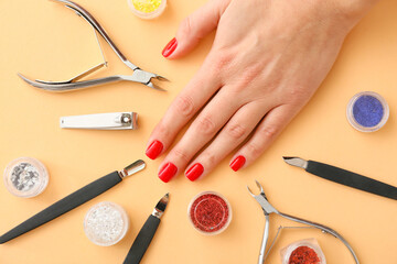 Female hand and tools for manicure on color background, closeup